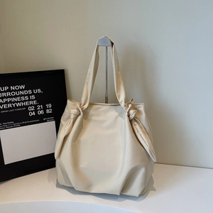 Detail of knot handle design and soft cream PU leather on casual shoulder tote bag