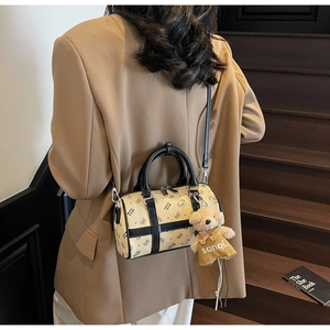 Detail of Boston bag with black bear patterns and cute plush keychain on a brown suit