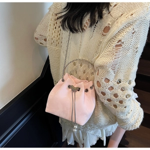 Detail of light pink bucket bag with silver butterfly charm and pearl tassel accents