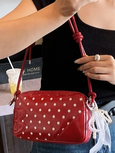 Chic red polka dot baguette bag with lacquered finish and elegant pearl ribbon charm