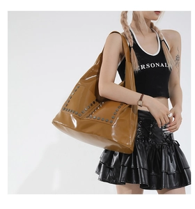 Detail of caramel brown hobo tote bag featuring polished finish and hexagonal metal rivets