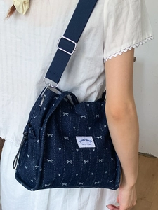 Cute dark blue denim crossbody tote bag with white bow patterns and wide nylon strap