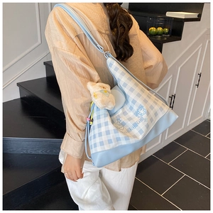 Detail of light blue checkered canvas tote bag with Luckygirl text and plush bear charm