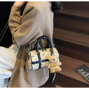 Detail of beige Boston bag with cartoon bear prints and a plush bear pendant charm