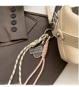 Detail of woven charms with metal abacus pendant on a beige leather stylish handbag