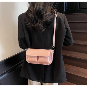 Macro view of pink patent leather crossbody bag with PARIS embossing on a model
