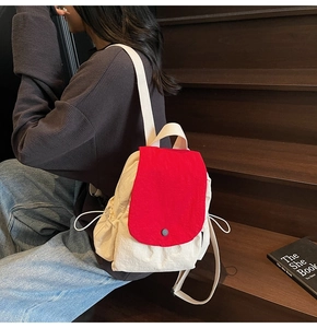 Detail view of contrast red and white canvas backpack on wooden steps in casual setting