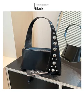 Detail view of black patent leather handbag with silver metal studs on a dark wooden surface