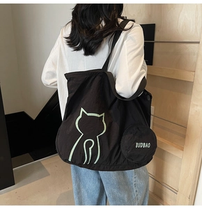 Detail of large black tote bag with green cat outline and matching round coin purse