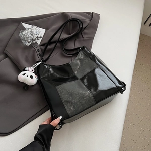 Detail of glossy black patchwork tote bag with cute panda plush charm accessory