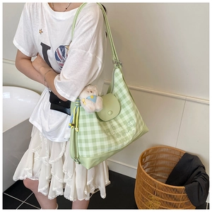 Detail of light green plaid tote bag with luckygirl print and plush bear charm