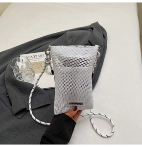 Detailed view of white mesh crossbody bag with thick rope strap and branded woven label