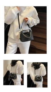 Detailed macro view of black lychee grain leather handbag with silver hardware and charm