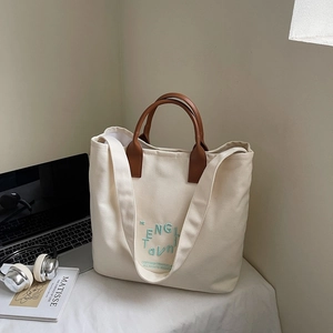 Detail of cream canvas tote bag with brown leather handles and English embroidery