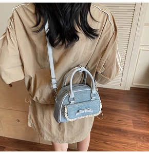Model view of a light blue denim bow bag with white lace trim and crossbody strap