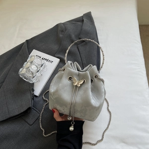 Detail of silver grey drawstring bucket bag with butterfly and pearl charms on a suit