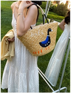Detailed shot of a straw tote bag with goose embroidery and Hola text for summer vacations