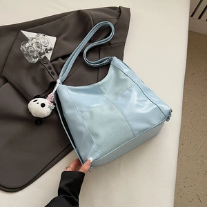 Detailed view of light blue stitched tote bag with cute panda charm on a brown suit jacket
