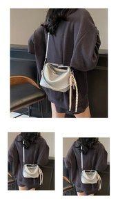 Detailed shot of silver pebbled leather handbag with decorative woven cord pendant