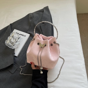 Detailed view of pink satin bucket bag with silver butterfly charm and metal handle