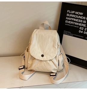 Detail of cream canvas backpack featuring flap closure and drawstring side pockets