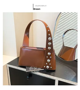 Detail shot of brown leather shoulder bag with silver studs on black wood surface