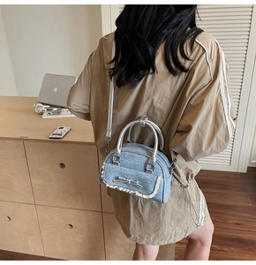 Detail view of denim light blue handbag with silver bow decoration and white lace trim
