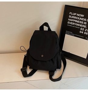 Detail of minimalist black canvas backpack with flap buckle closure and side drawstring pockets