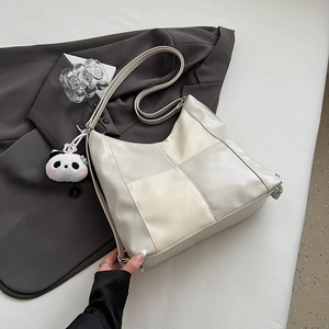 Detail of cream white tote bag with grid stitching and cute panda plush charm pendant