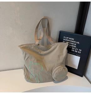 Detail view of khaki nylon tote bag with cat graphic and matching round coin purse