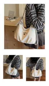 Close-up of cream white hobo bag showing soft PU leather folds and heart charm detail