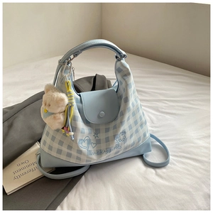 Detail of light blue checkered tote bag with Luckygirl embroidery and plush bear charm