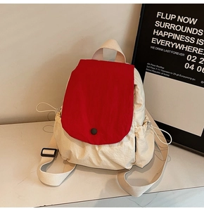 Close-up of cream canvas backpack with red flap and drawstring side pocket detail