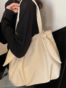 Chic beige fabric shoulder tote bag with a large decorative bow on the strap