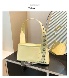 Close-up of a yellow punk-style handbag featuring oversized silver stud hardware details