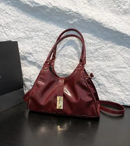 Detailed macro view of wine red glossy patent leather handbag with gold metal buckle