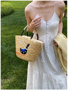Detail of hand-woven straw tote with swan embroidery and drawstring inner lining