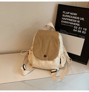 Detail of canvas backpack with cream body, khaki flap, and round button closure detail
