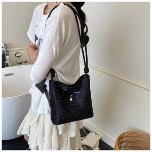 Dettaglio borsa a secchiello nera a pois con fiocco e ciondolo con perla elegante