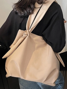 Minimalist beige tote bag with knot strap detail shown from a rear model view