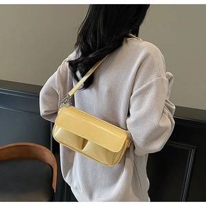 Detail of yellow glossy baguette bag with Paris embossing on model shoulder
