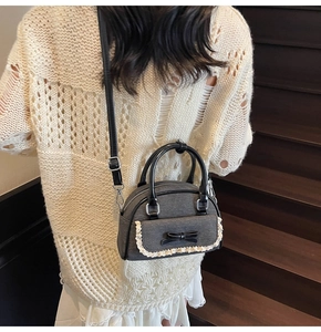 Model wearing dark grey bow handbag with lace trim on a cozy wooden staircase setting