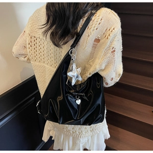 Detail of black patent leather bag with bow, heart pendant and silver star charm