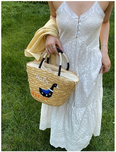 Detail of hand-woven straw bag with duck embroidery and white drawstring inner lining