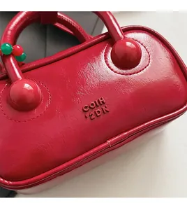 Macro detail of red pillow bag showing pebbled leather texture and embossed logo