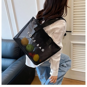 Sac fourre-tout en maille noire semi-transparente avec inscription TOTE BAG sur l'épaule