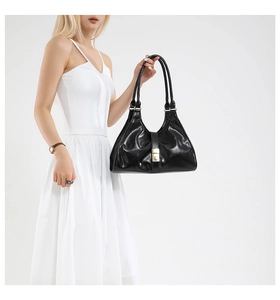 Detail of a black leather hobo bag featuring a signature golden square metal buckle