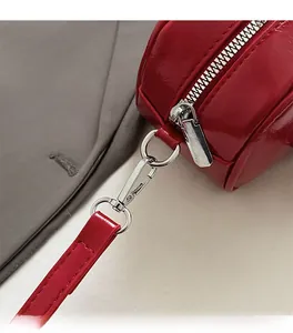 Detail of red glossy leather handbag featuring premium silver metal zipper and clasp