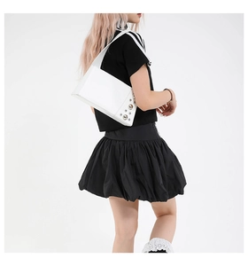 Close-up of white punk style underarm bag featuring silver rivets and wide shoulder strap