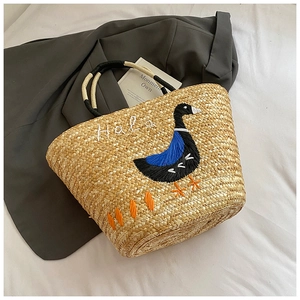 Detail of handmade straw bag with elegant goose embroidery and woven rope handles